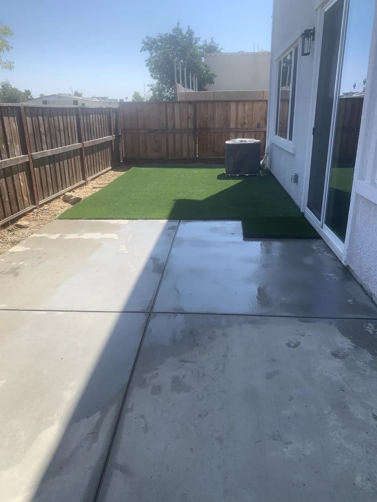 Narrow artificial turf strip laid beside a concrete side patio