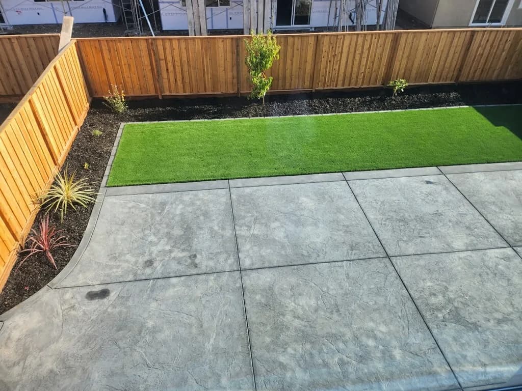 Artificial turf lawn beside a broom-finished concrete patio