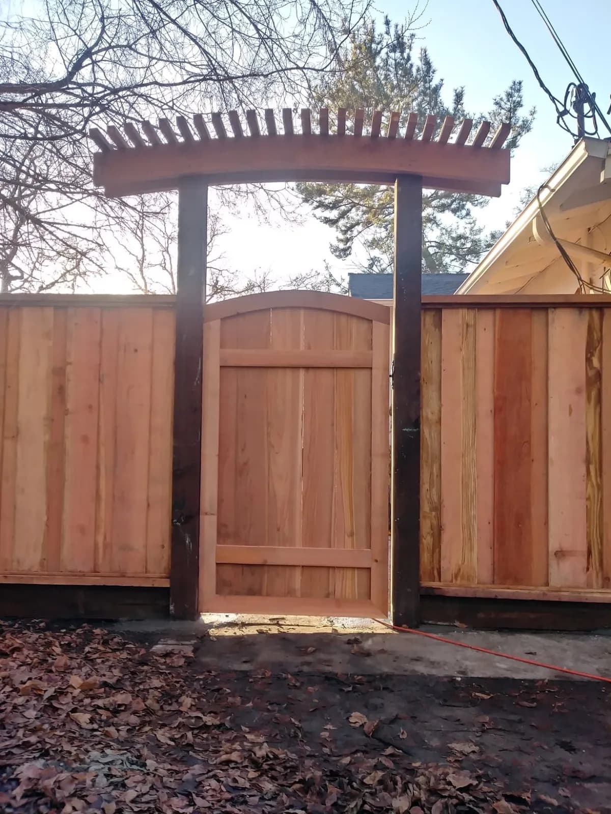 Custom arched gate with an arbor top set into a new redwood fence