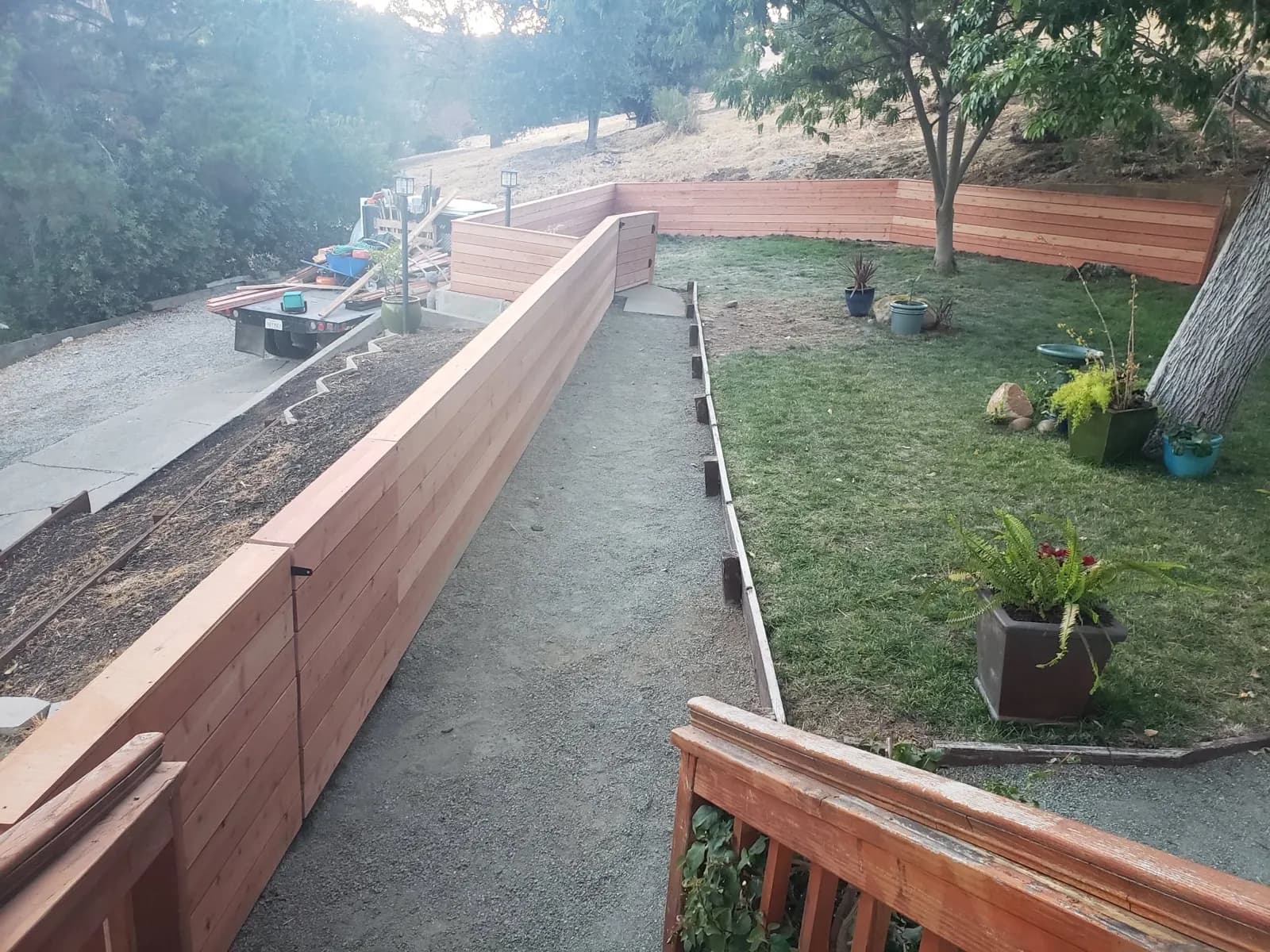 Horizontal-board fence enclosing a hillside backyard with a gravel path