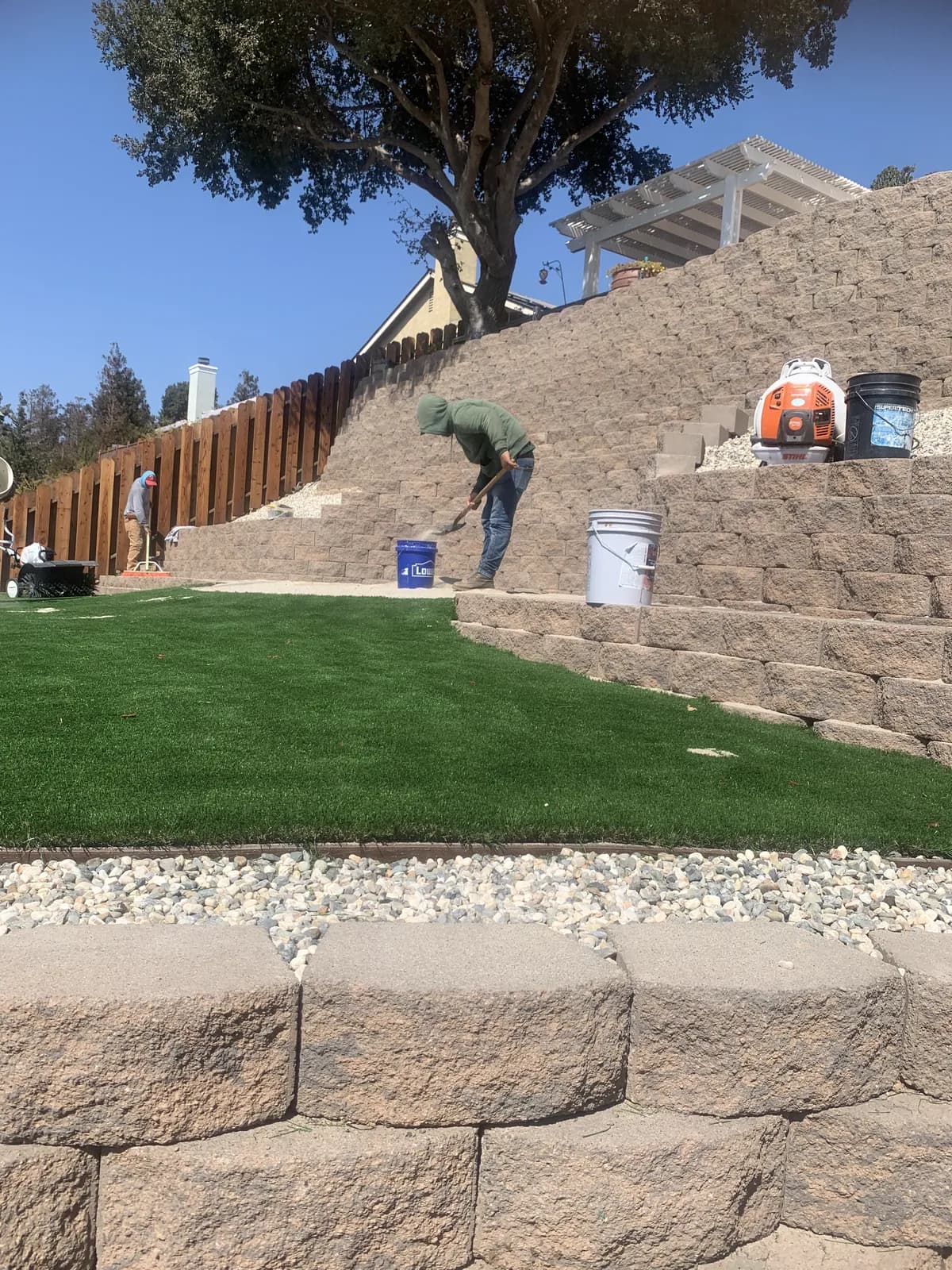 Putting green set into a terraced slope beneath a mature tree